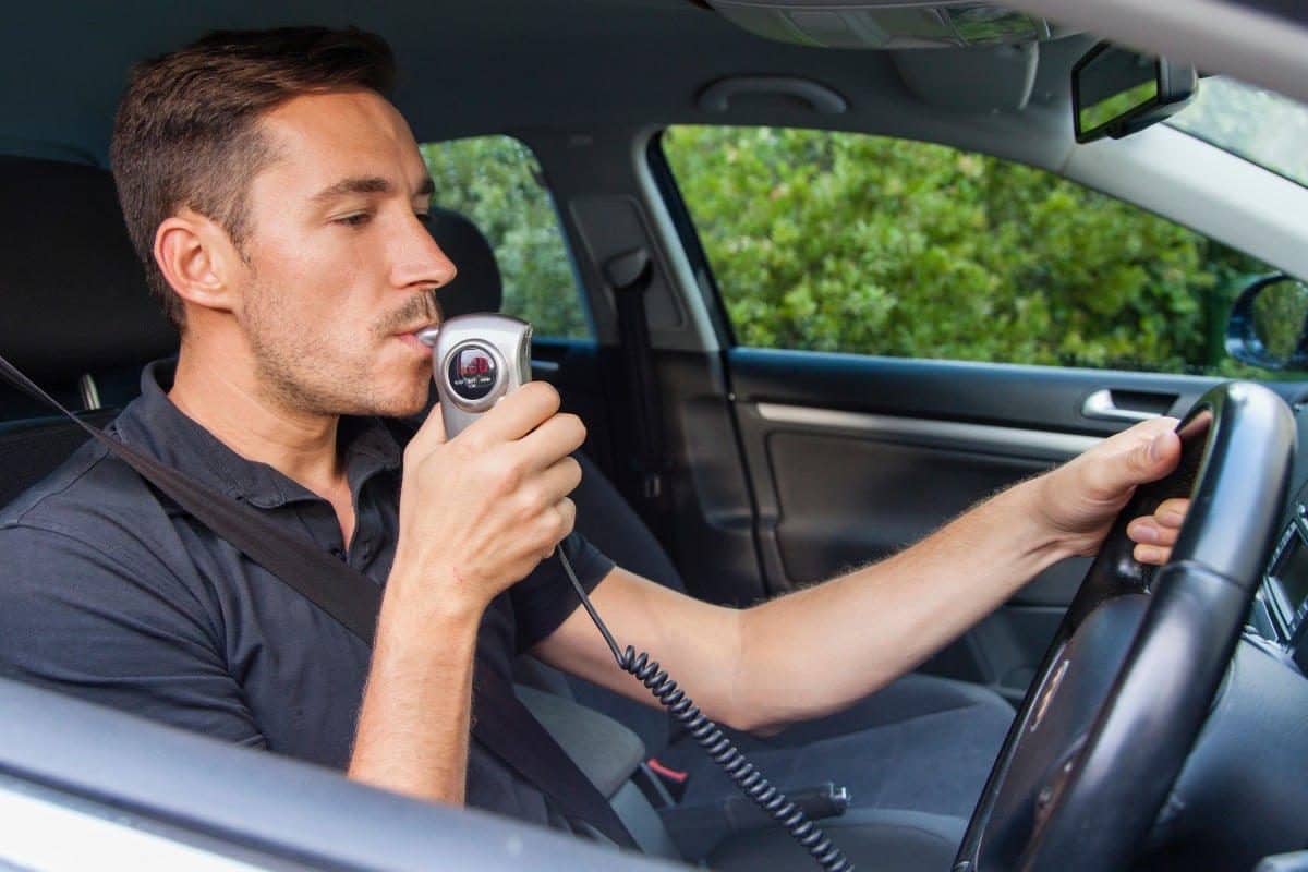 Driver using an ignition interlock handset before starting the car